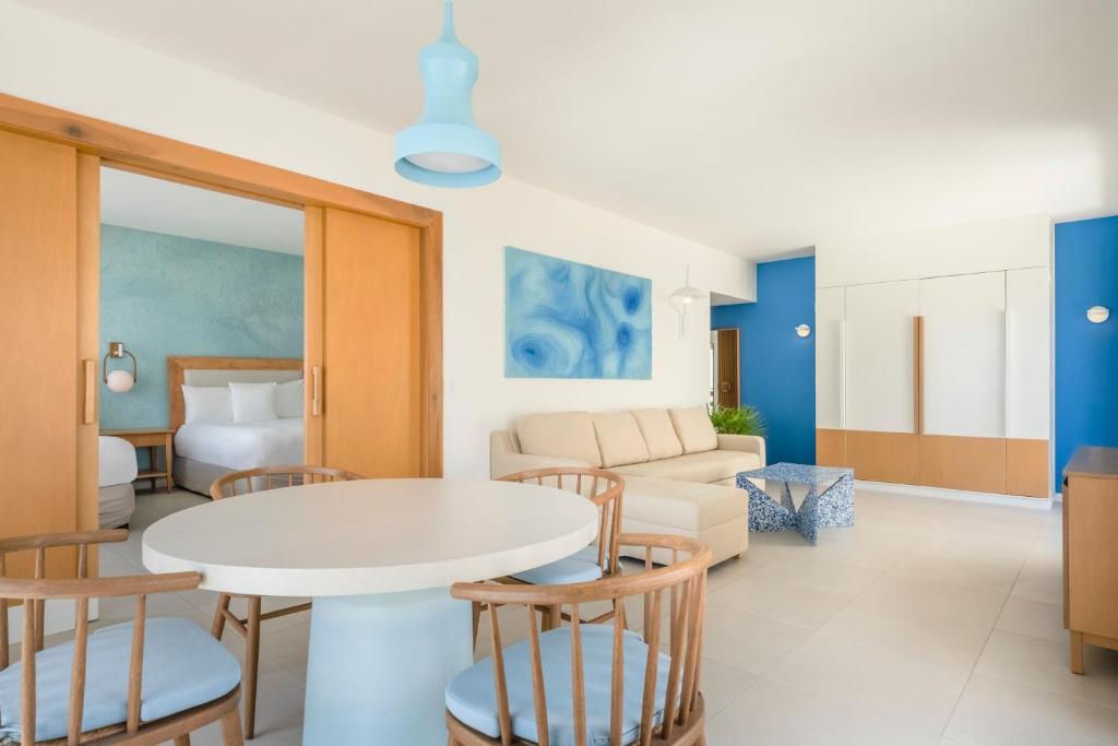 Mūsdienīgs viesnīcas numurs ar gaišām krāsām, kurā ir dzīvojamā zona ar dīvānu, galdu un krēsliem, kā arī guļamistaba ar divām gultām. Interjerā redzami zili akcenti un koka elementi, radot patīkamu atmosfēru.