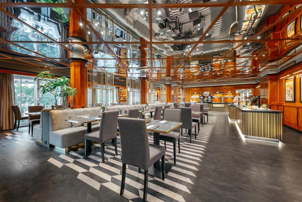 Mūsdienīgs restorāna interjers ar spoguļotu griestu un elegantu mēbeļu noformējumu, radot patīkamu atmosfēru un stilīgu vidi ēdienreizei.