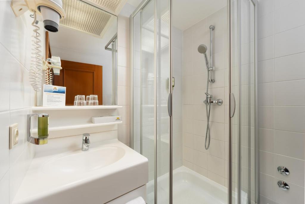 Mūsdienīga vannas istaba ar dušas kabīni, izsmalcinātu izskatu un higiēnas piederumiem. Telpā ir arī spogulis, izlietne un matu žāvētājs.