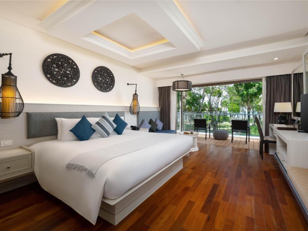 Moderns viesnīcas numurs ar plašu gultu, dekoratīviem elementiem un skatu uz dārzu. Telpa ir gaiša un eleganta, ar koka grīdu un mūsdienīgu interjeru.