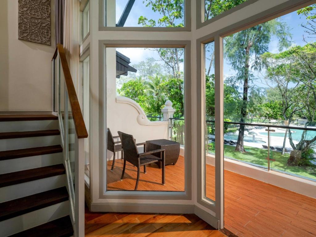 Gaismas piepildīta telpa ar skatu uz dārzu un baseinu, kurā redzami divi ērtie krēsli uz terases.