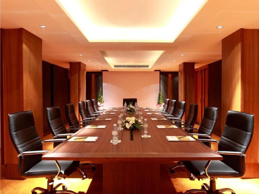 Moderns konferenču telpas dizains ar garu galdu un melniem krēsliem, ideāli piemērots biznesa sanāksmēm. Telpa ir apgaismota ar siltu gaismu, radot profesionālu atmosfēru.