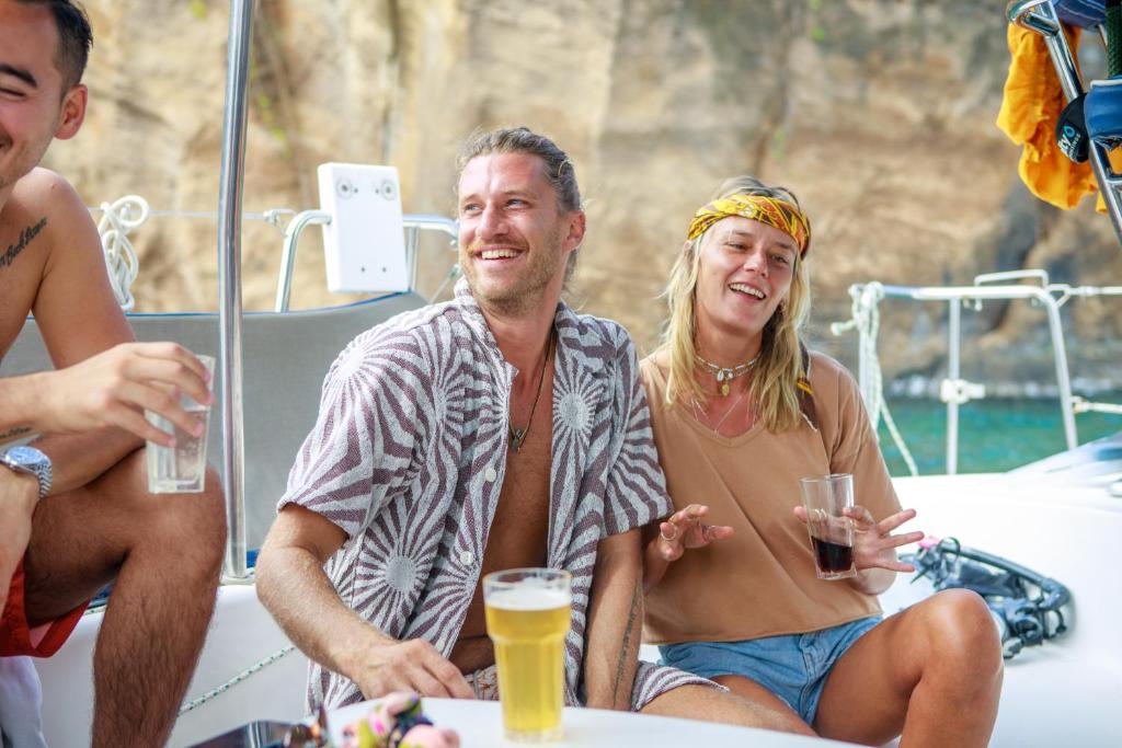 Priecīgas brīvdienas uz jahtas, kur divi draugi smejas un izbauda dzērienus pie jūras.