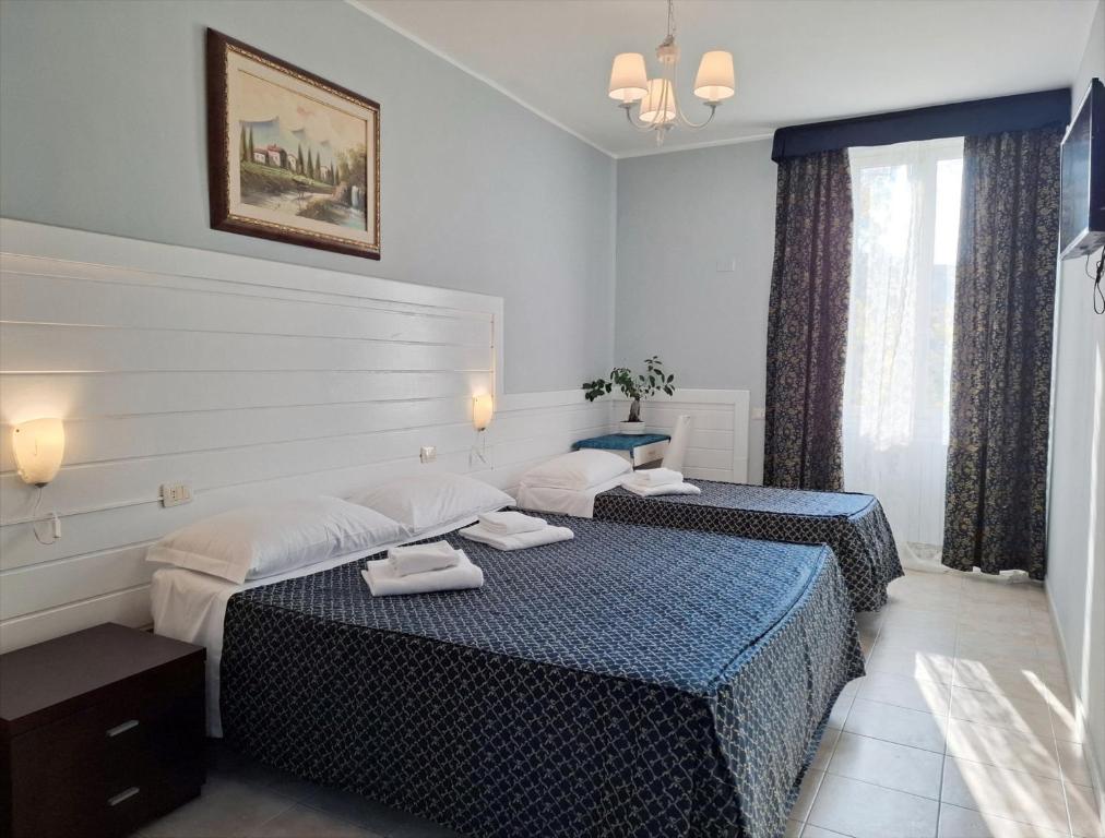 Labi iekārtota guļamistaba ar divām gultām, modernais apgaismojums un logi ar aizkariem, kas nodrošina dabisko gaismu. Sienās ir glezna un dekoratīvi elementi, radot mājīgu atmosfēru.