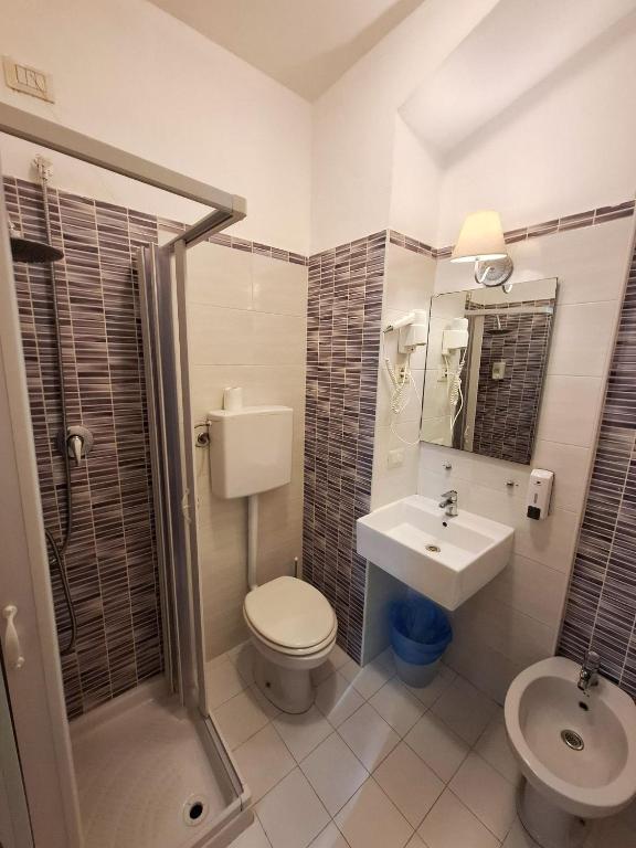 Mūsdienīga vannas istaba ar dušas kabīni, izlietni un tualeti, dekorēta ar gaišām flīzēm un funkcionāliem piederumiem.