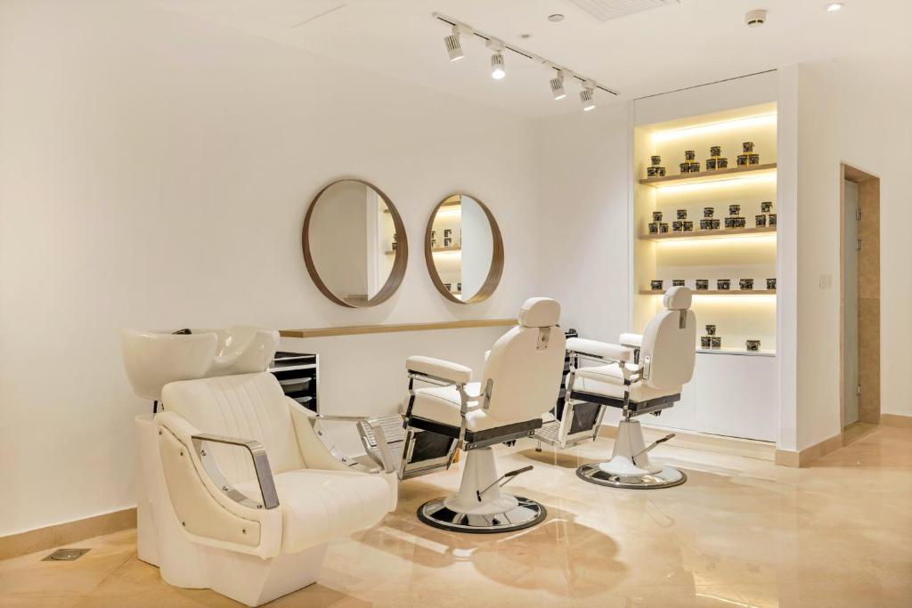 Skaistumkopšanas salons ar modernām matu griešanas krēsliem un elegantu dizainu, kurā ir redzami spoguļi un produktu plaukti.