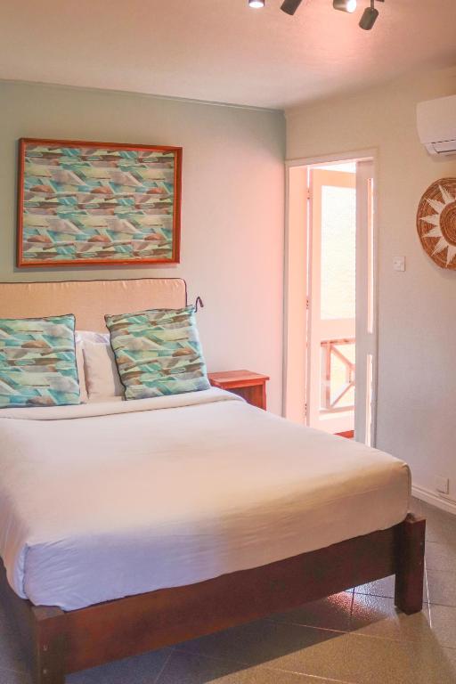 Gaišs numurs Flowers of Paradise viesnīcā ar mākslas darbiem pie sienas.