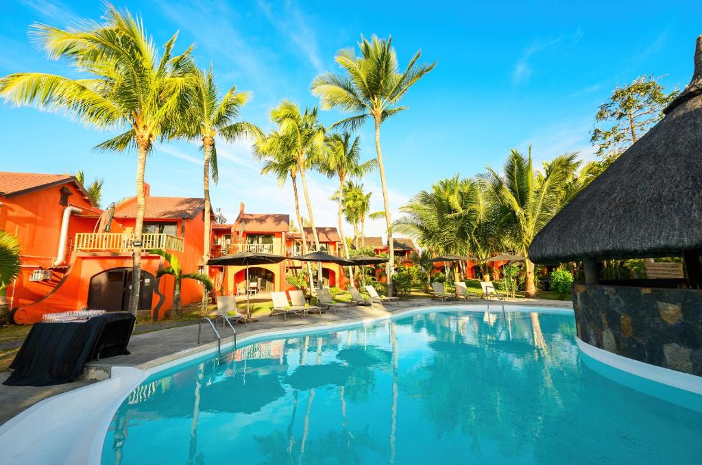 Tropisks baseins viesnīcā Flowers of Paradise ar palmām un sauļošanās krēsliem.