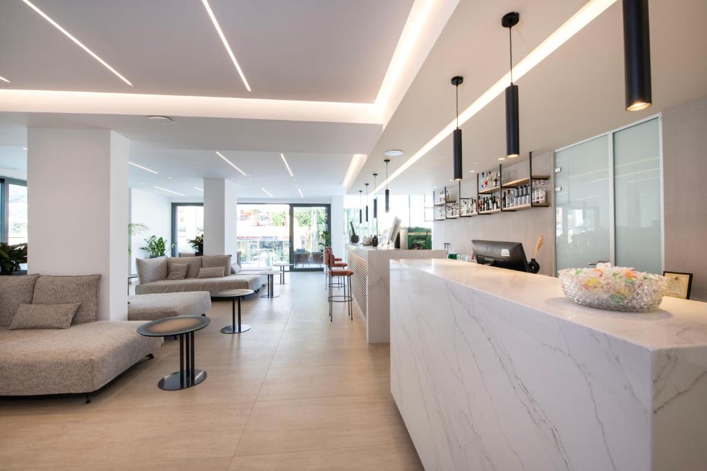 Mūsdienīgs viesnīcas reģistratūras un atpūtas zona ar gaišām ēkām un elegantiem mēbeļu risinājumiem. Telpā ir plašs dabiskais apgaismojums un mūsdienīga dizaina elementi.