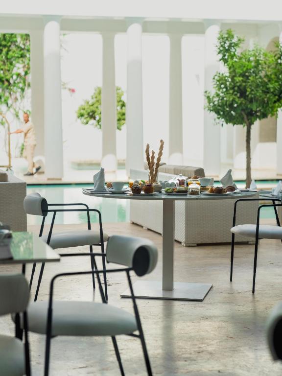 Mūsdienīga restorāna vide ar apkalpošanu, kurā redzams galdiņš ar dažādiem gardumiem, un aizmugurē ir peldbaseins un zaļumi.