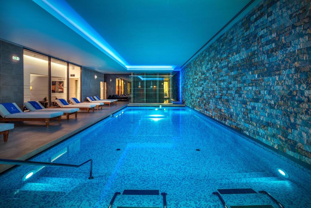 Mūsdienīgs iekštelpu peldbaseins ar zilu apgaismojumu un akmens sienu, ap kuru izvietotas atpūtas gultas. Ideāla vieta relaksācijai un atpūtai.