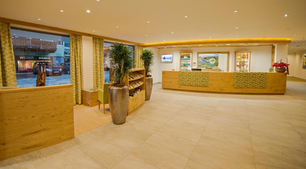 Moderns viesnīcas reģistratūras interjers ar koka elementiem un augiem. Gaismas apgaismojums un plašas logu ainas rada viesmīlīgu atmosfēru.