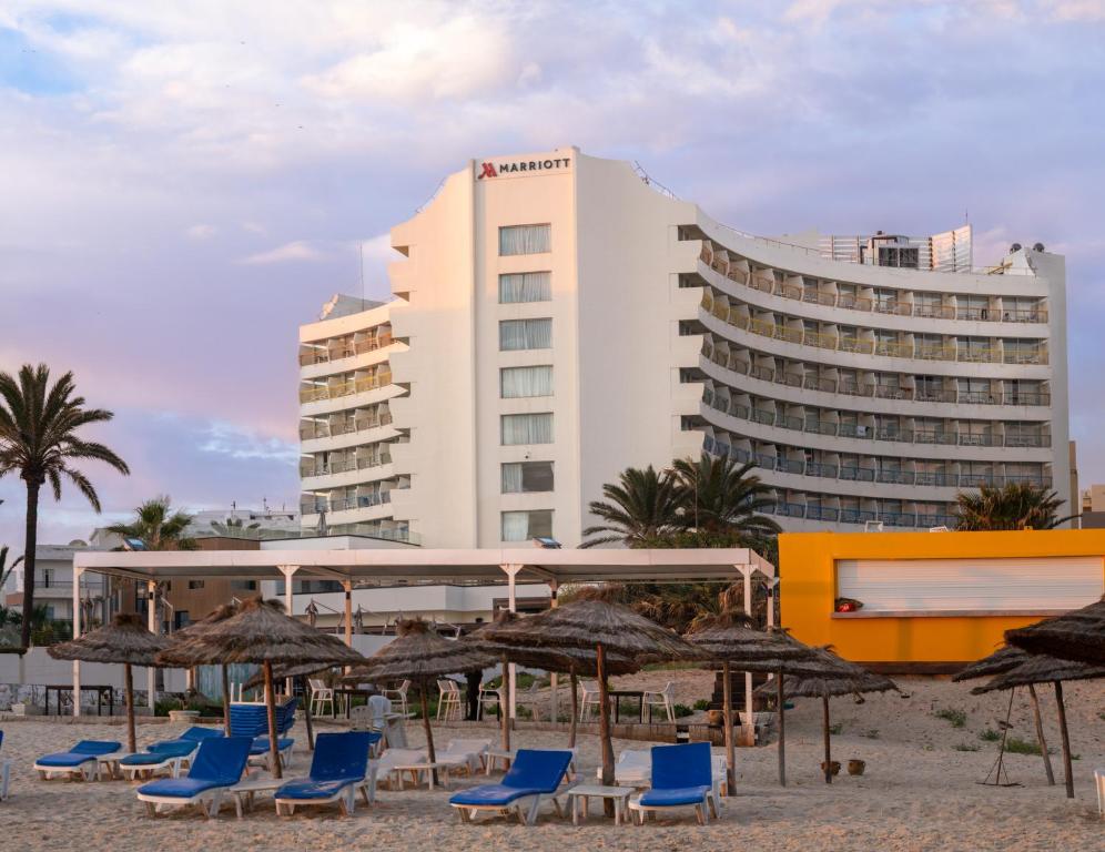 Pludmales viesnīca ar modernu arhitektūru un saulainām atpūtas zonām, kur apmeklētāji var baudīt brīvdienas pie jūras.