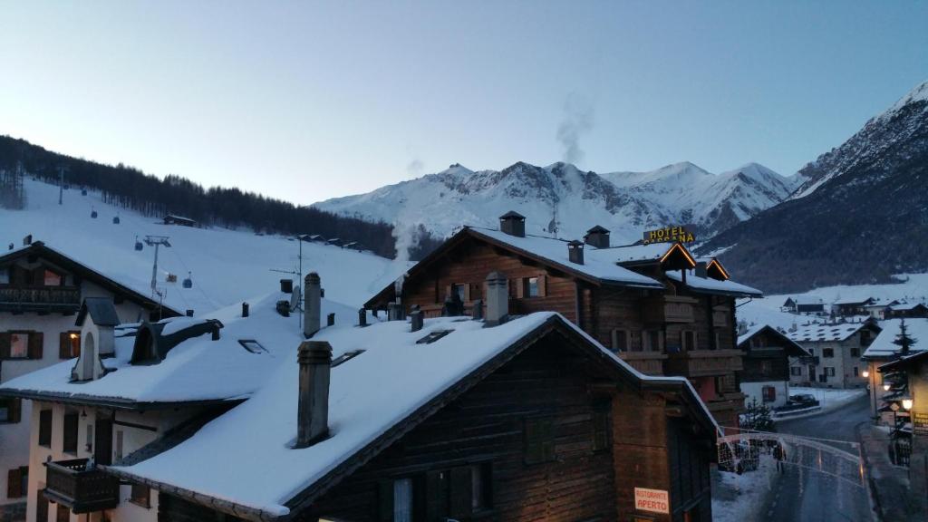 Kalnu ainava ar sniegotiem jumtiem un viesnīcu signāli, kas atspoguļo ziemas ainavu.