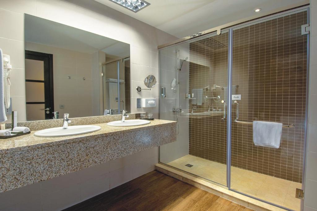 Mūsdienīgs vannas istabas interjers ar divām izlietnēm, dušas kabīni un siltu koka grīdu. Stilīgas detaļas un gaišas krāsas rada patīkamu atmosfēru.