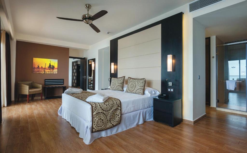 Mūsdienīga viesnīcas istaba ar plašu gultu un koka grīdu, papildināta ar viesistabas mēbelēm un mākslas darbu uz sienas. Komfortabls un elegants interjers.