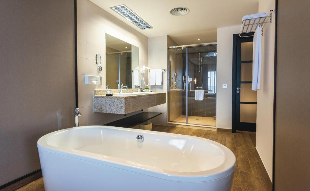 Mūsdienīgs vannas istabas interjers ar brīvo stāvošu vannu, dušu un akmens izstrādājumiem. Svaiga, gaiša atmosfēra un eleganta dizaina elementi.