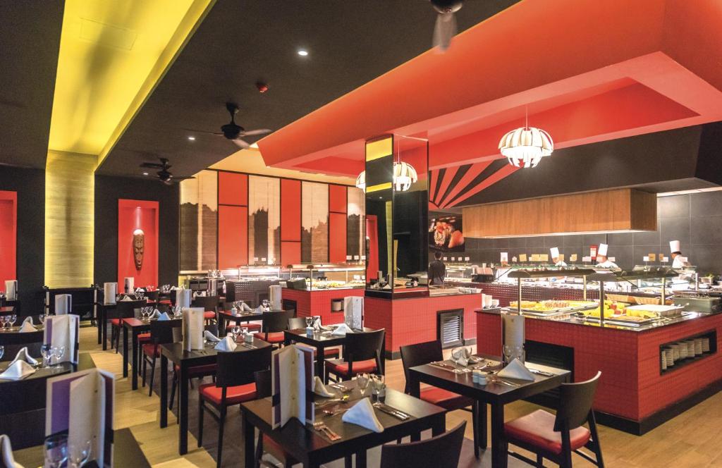 Mūsdienīga restorāna iekārtojums ar sarkaniem un melniem akcentiem, elegantām galdiem un apgaismojumu. Svaigu ēdienu bufete un stilīgs dizains rada patīkamu atmosfēru.
