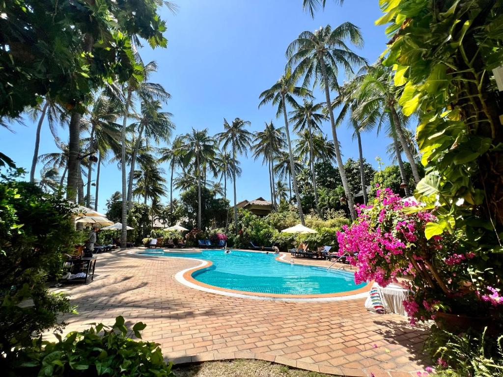 Tropu paradīze ar palmām un ziediem, kas ieskauj peldbaseinu saulainā dienā. Ideāla vieta atpūtai un relaksācijai.