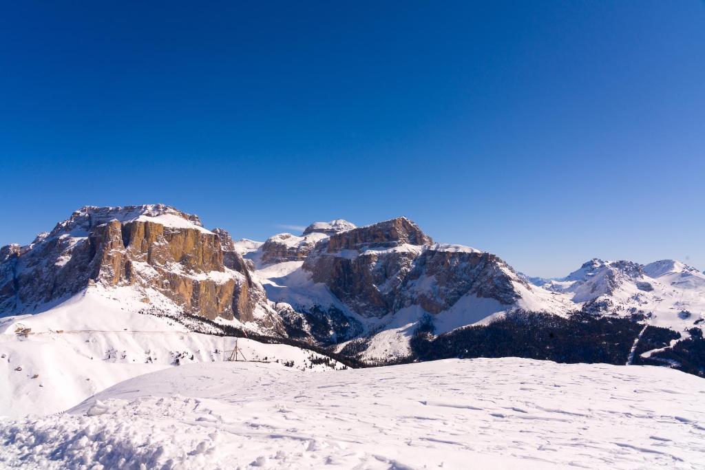 Sniega klāts kalnu ainava ar skaidru zilo debesu fonu, kas rada mierīgu un elpu aizraujošu atmosfēru.