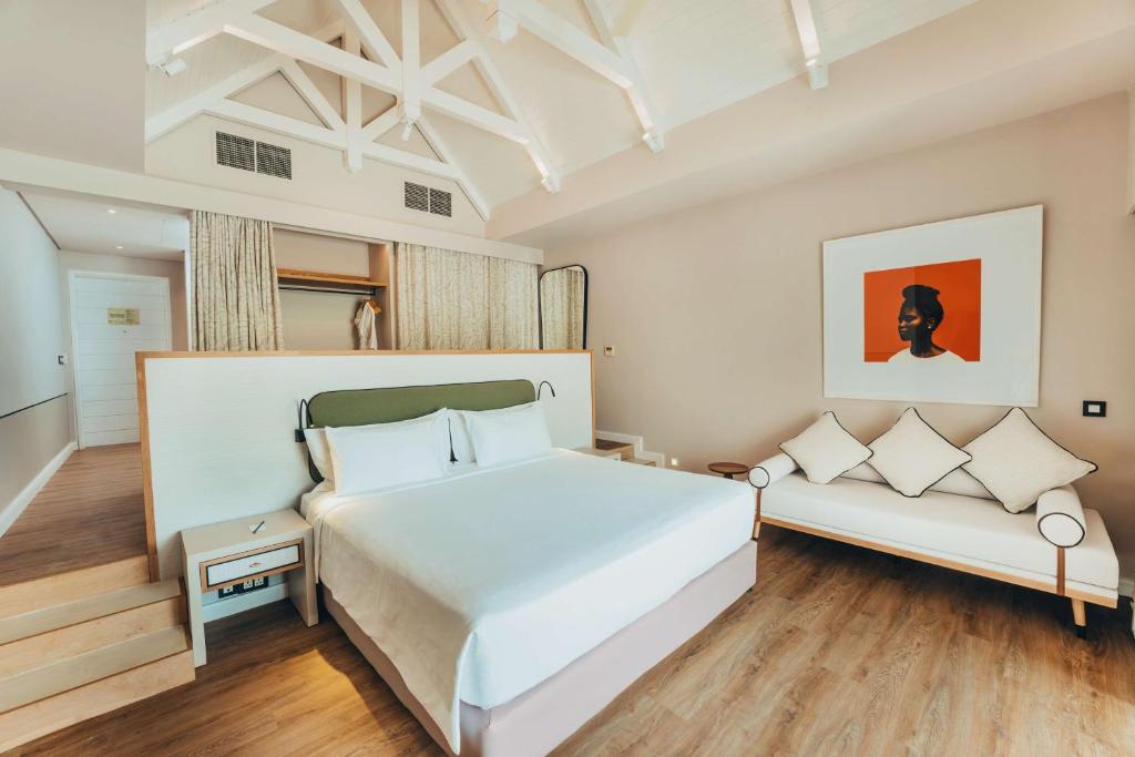 Mūsdienīga guļamistaba ar augstiem griestiem, ērtu gultu un stilīgu dīvānu. Interjers ir gaišs un elegants, ar mākslas darbu uz sienas, kas piešķir telpai raksturu.