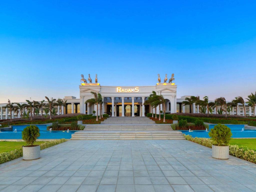 Elegants viesnīcas ēkas priekšpuse ar pakāpieniem un dārzu. Virs ieejas ir nosaukums 