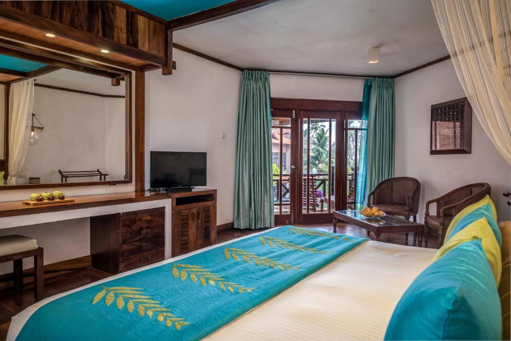 Mūsdienīgs viesnīcas numurs ar koka apdari, gaišām aizkariem un skatu uz terasi. Interjerā ir televizors, rakstāmgalds un komfortabli krēsli, radot relaksējošu atmosfēru.