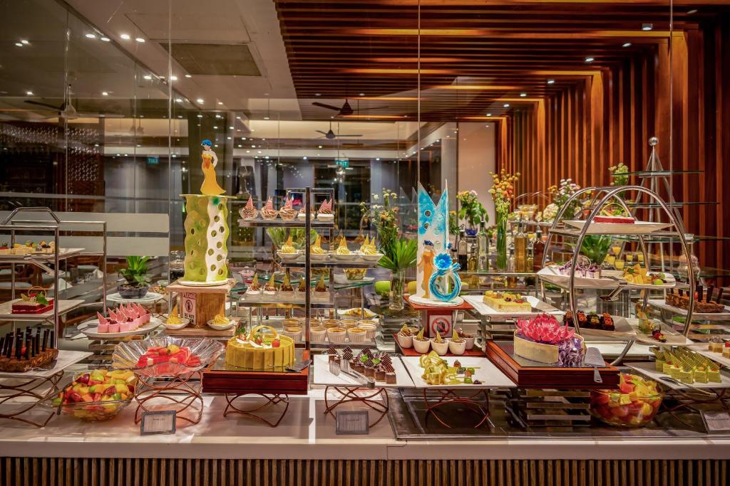 Saldumu bufete ar dažādiem krāsainiem desertiem un kūkām, skaisti izkārtoti modernā restorānā. Dekorācijas un augi piešķir patīkamu atmosfēru.