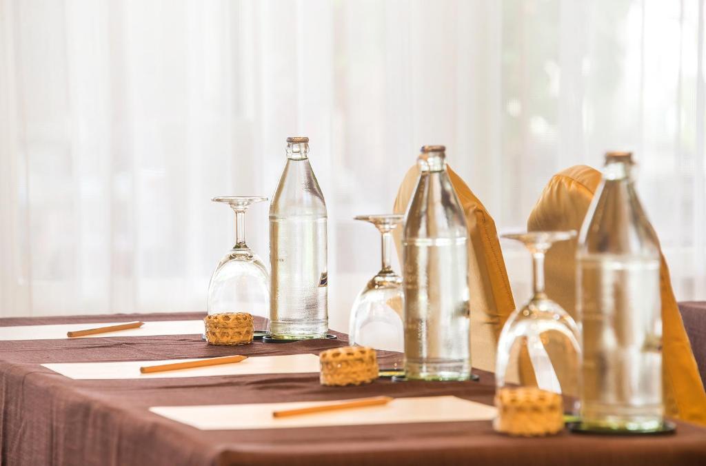 Konferenču galda iestatījums ar ūdens pudelēm un glāzēm, kas gatavots sanāksmēm vai prezentācijām. Uz galda ir pieejami arī rakstāmpiederumi un papīra lapas.