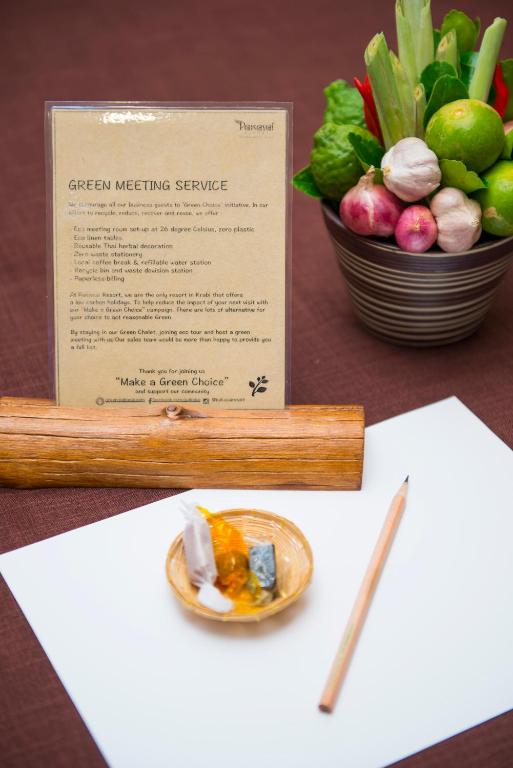 Zaļā sanāksmju pakalpojuma plāns, kopā ar dārzeņu pušķi un rakstāmo, uz galda ar balto papīru.