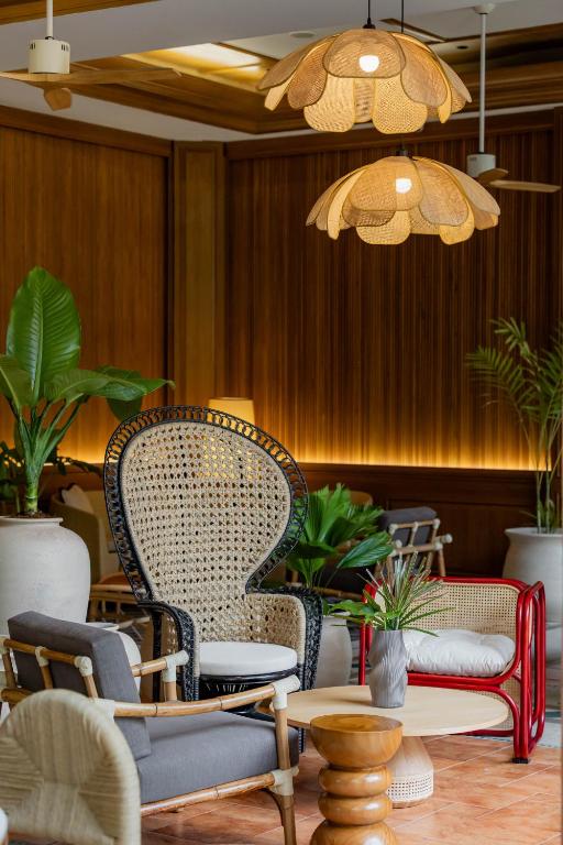 Mūsdienīgs interjers ar elegantiem mēbeļu dizainiem, ieskaitot rotangpalmas krēslu un stilīgas lampas. Telpa ir apzaļumota ar augiem, radot relaksējošu atmosfēru.