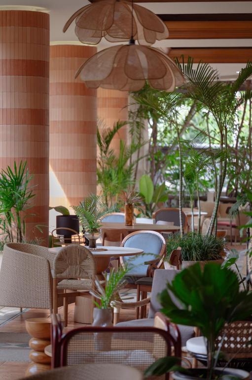 Mūsdienīgs restorāna interjers ar augiem, elegantu mēbeļu kombināciju un gaišu apgaismojumu. Telpa ir iekārtota ar radošiem elementiem, kas rada relaksējošu atmosfēru.