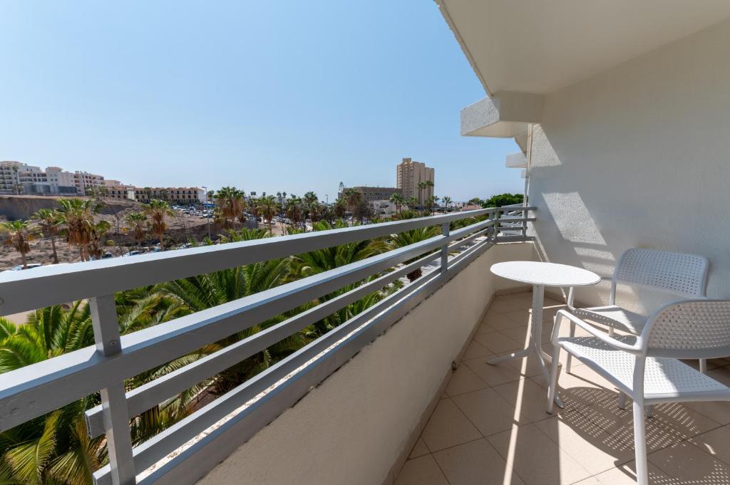 Balconā redzama relaksējoša zona ar galdu un krēsliem, no kuras paveras skats uz palmu stādījumiem un apkārtējo ainavu. Ideāli piemērots atpūtai un atpūtas brīžiem.