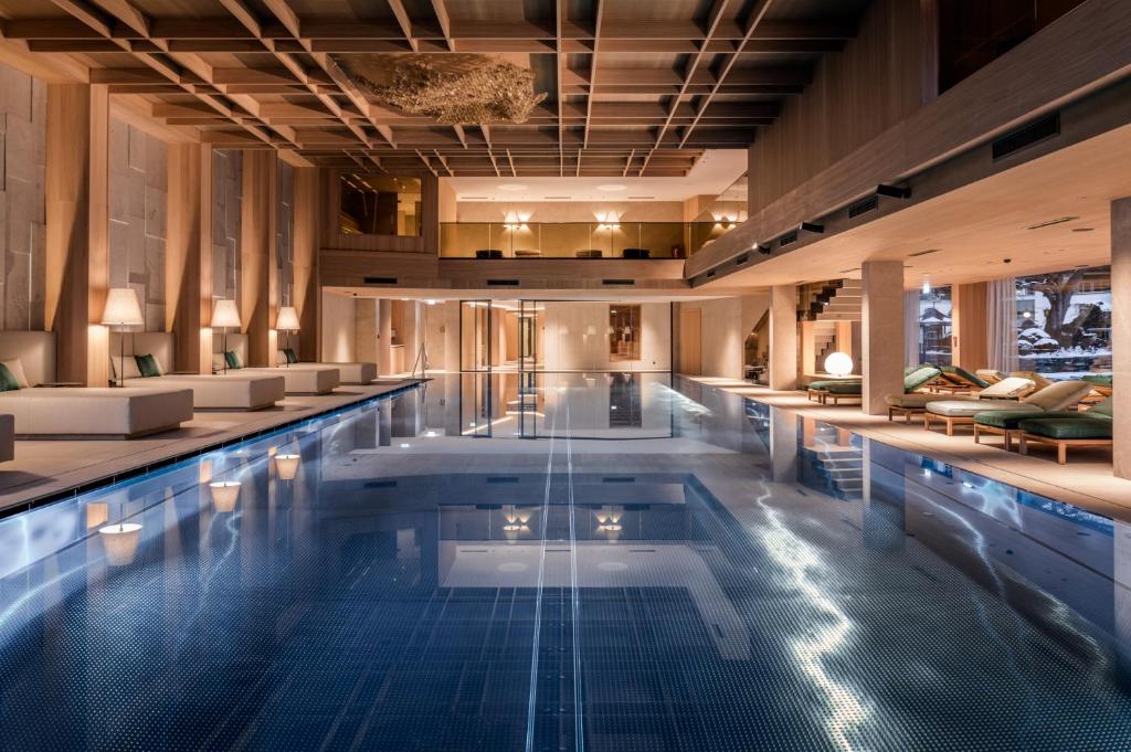 Mūsdienīgs un elegants iekštelpu baseins ar koka un akmens elementiem, izgaismots ar siltām gaismām, radot relaksējošu atmosfēru. Ap baseinu ir komfortablas atpūtas zonas ar mīkstiem dīvāniem un krēsliem.