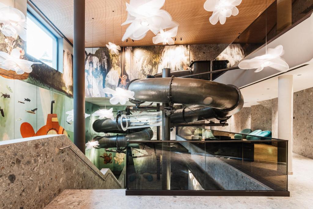 Moderns interjers ar caurulēm un gaismas ķermeņiem, kas veido unikālu atmosfēru. Sienas rotā krāsaini zīmējumi, kas piešķir telpai dzīvīgumu.