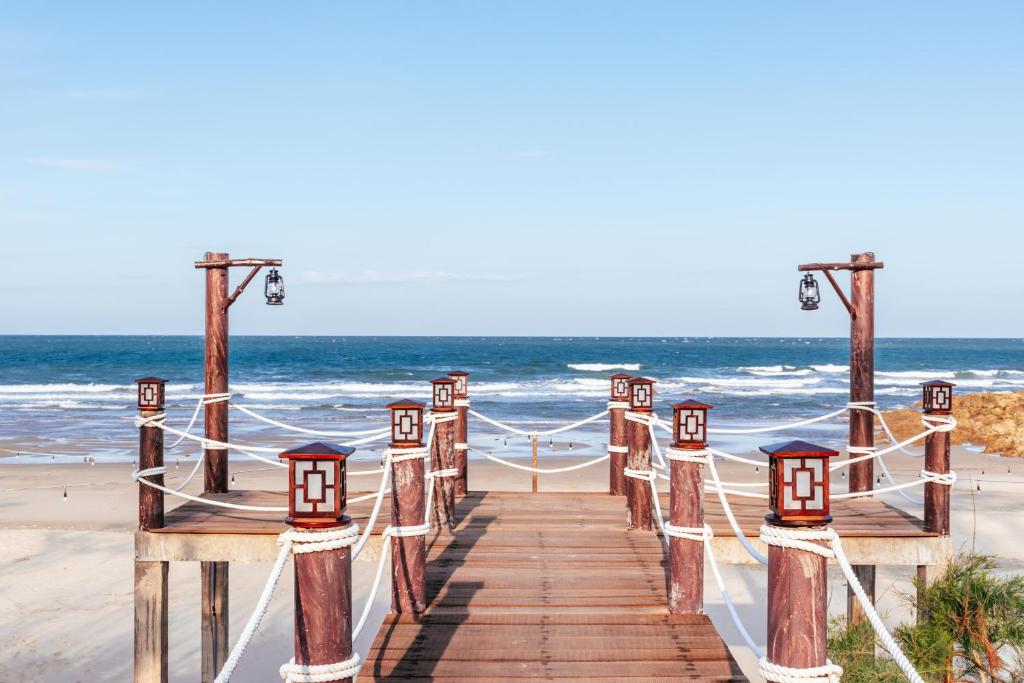 Koka piestātne ar lampām un jūru fona. Šis skats rada mierīgu pludmales atmosfēru.