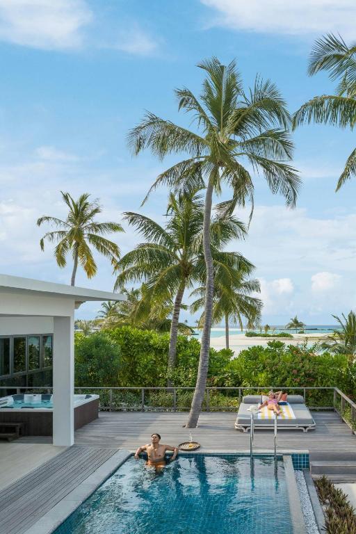 Atpūtas vieta ar baseinu, palmām un pludmales skatu, radot ideālu atpūtas atmosfēru. Ideāli piemērota tropiskai brīvdienu pieredzei.