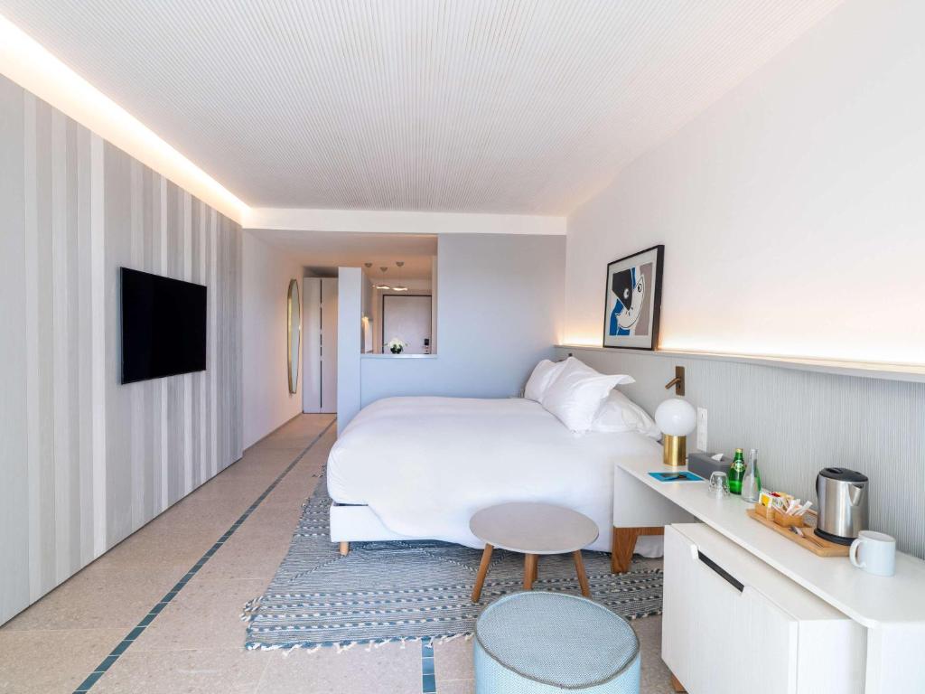 Mūsdienīgs viesnīcas numurs ar gaismu, kas akcentē modernu interjeru, iekārtots ar ērtu gultu, viesmīlības stūrīti un izsmalcinātām dekorācijām.