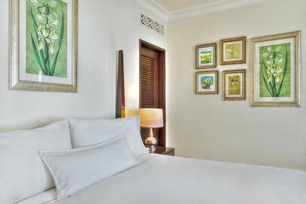 Gultas zona ar elegantu apgaismojumu un mākslas darbiem uz sienām, radot mierīgu un viesmīlīgu atmosfēru.