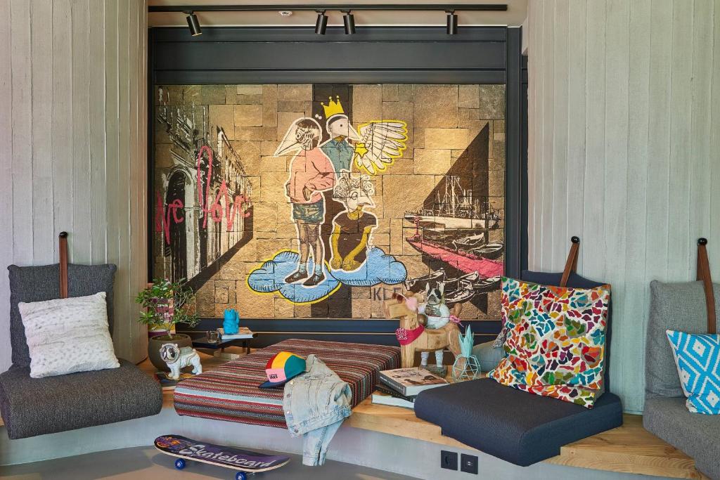 Interesanta interjera ar krāsainu mākslas darbiem uz sienas un ērtām sēdvietām, kas rada relaksētu atmosfēru. Sēdvietas papildina spilveni un dekoratīvi elementi.