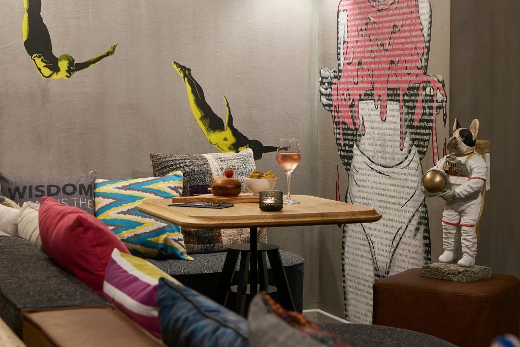 Mūsdienīga kafejnīca ar krāsainām spilveniem un oriģinālu mākslu uz sienām, kurā redzams stilizēts astronauta statuja un eleganta dzēriena glāze.