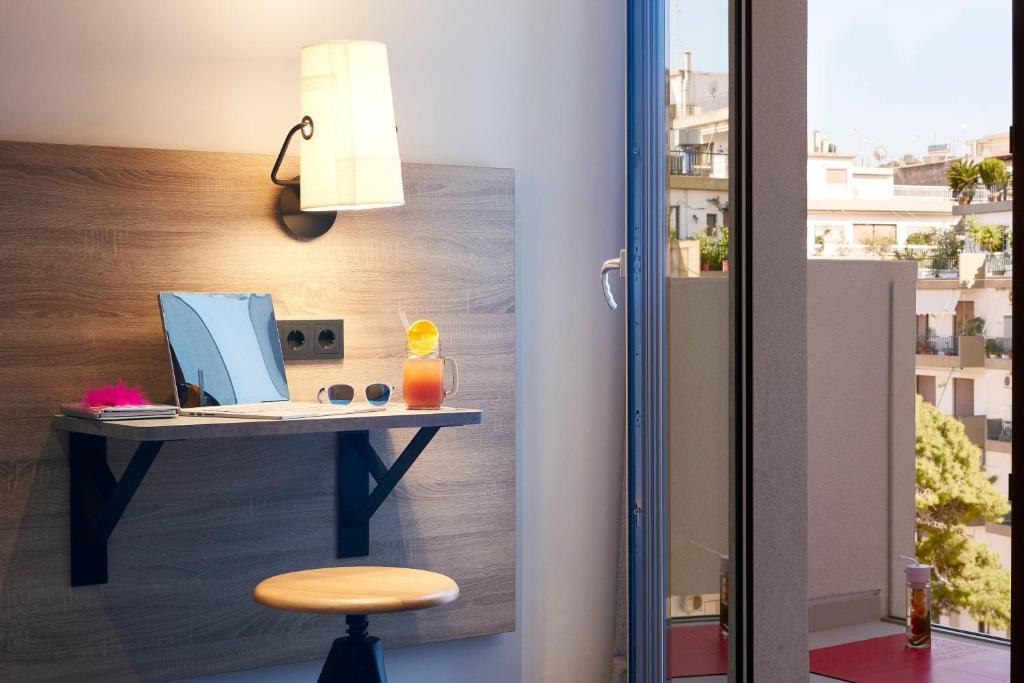 Mūsdienīga darba vieta ar galdu, spoguli un dzērienu, kas atrodas pie loga, no kura paveras skats uz ārpusi. Gaisma no sienas lampas rada patīkamu atmosfēru.