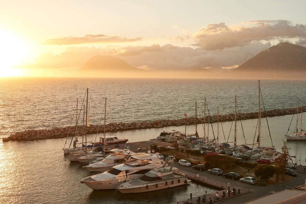 Pārsvarā saulrieta skats uz ostu ar jahtām un kalnu fona. Kluss un mierīgs jūras ainava ar zeltainām debesīm un miglu.