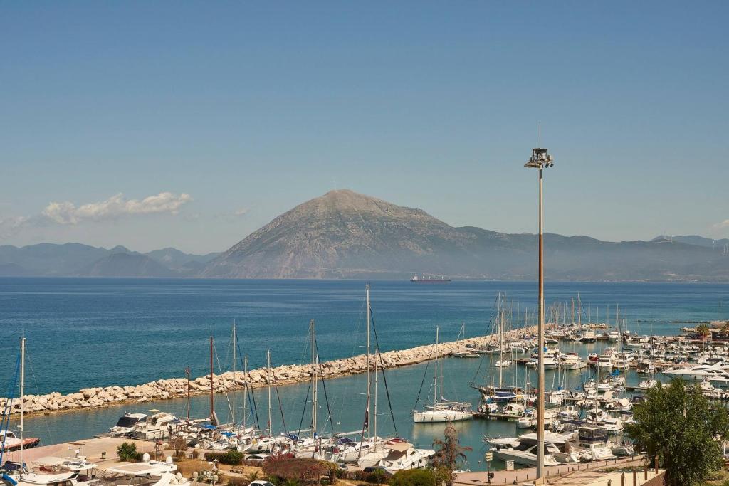 Osta ar kuģiem un kalnu ainava fona, saulainā dienā. Skats uz mierīgu jūru un krastu.