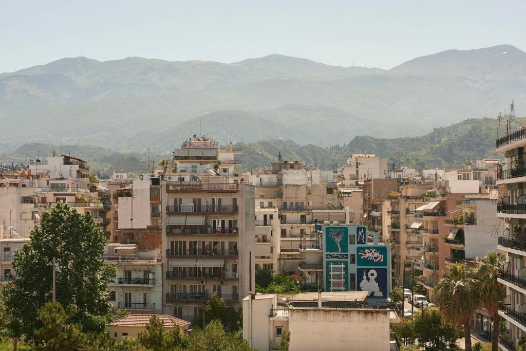 Pilsētas ainava ar kalnu fonu un daudzstāvu ēkām, kuras rotā grafiti un zaļumi. Ideāla vieta, lai izceltu mūsdienu arhitektūru un pilsētas dzīvi.