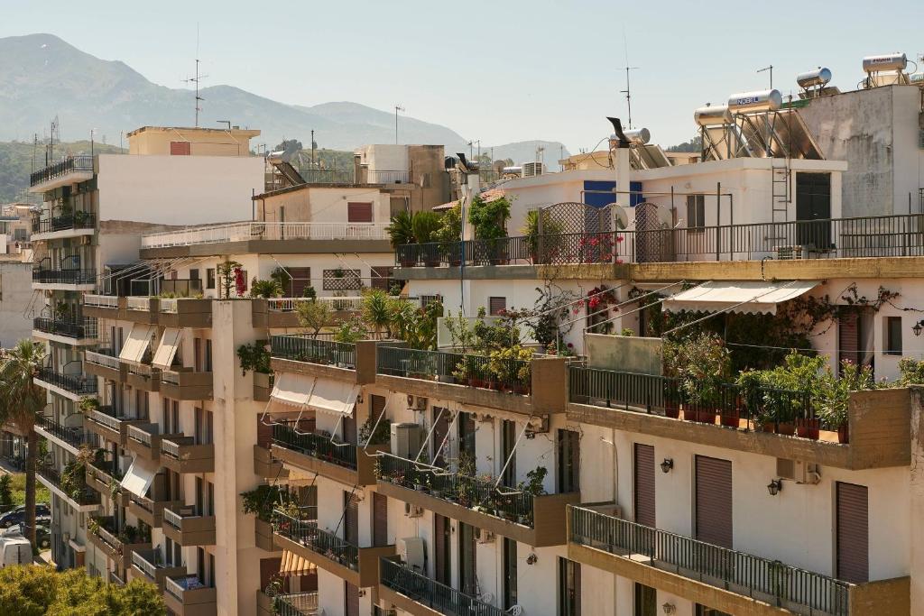 Dažādas dzīvojamās ēkas ar balkoniem, kas dekorēti ar augiem, un kalnu fons. Ideāla ainava pilsētas dzīves attēlošanai.