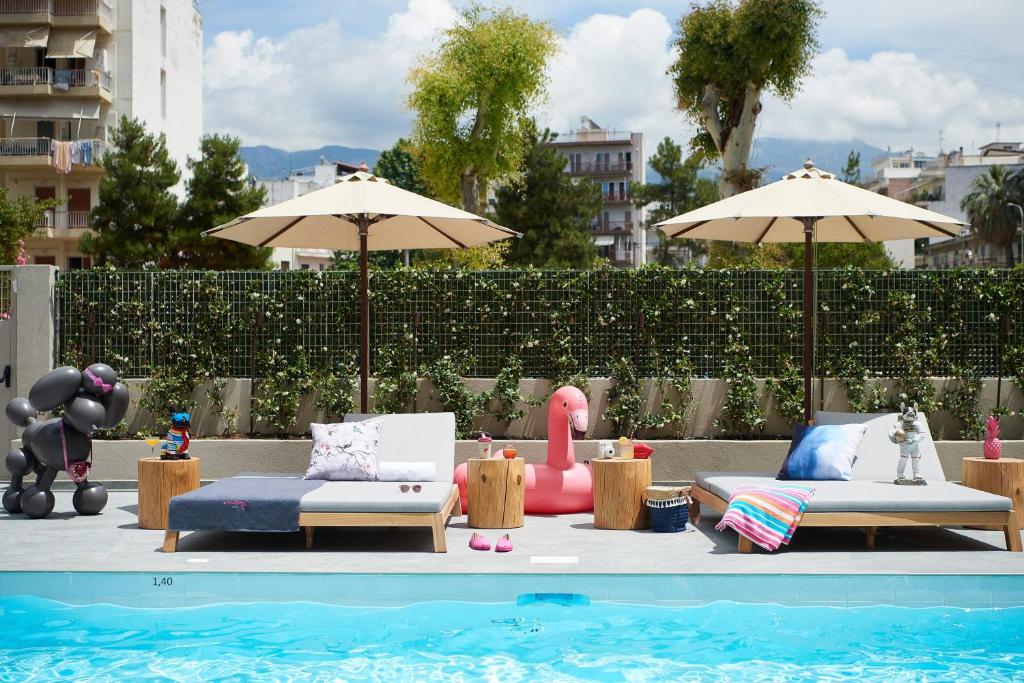 Vasarīgas atpūtas zona pie baseina ar modernas sauļošanās gultām, saules parasoliem un krāsainiem piederumiem, tostarp rozā flamingo un balonu suņuku.