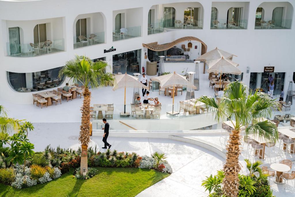 Mūsdienīgs restorāns ar ārējo terasi, kurā ir viesi un palmas, pārsteidz ar eleganto dizainu un relaksējošu atmosfēru.