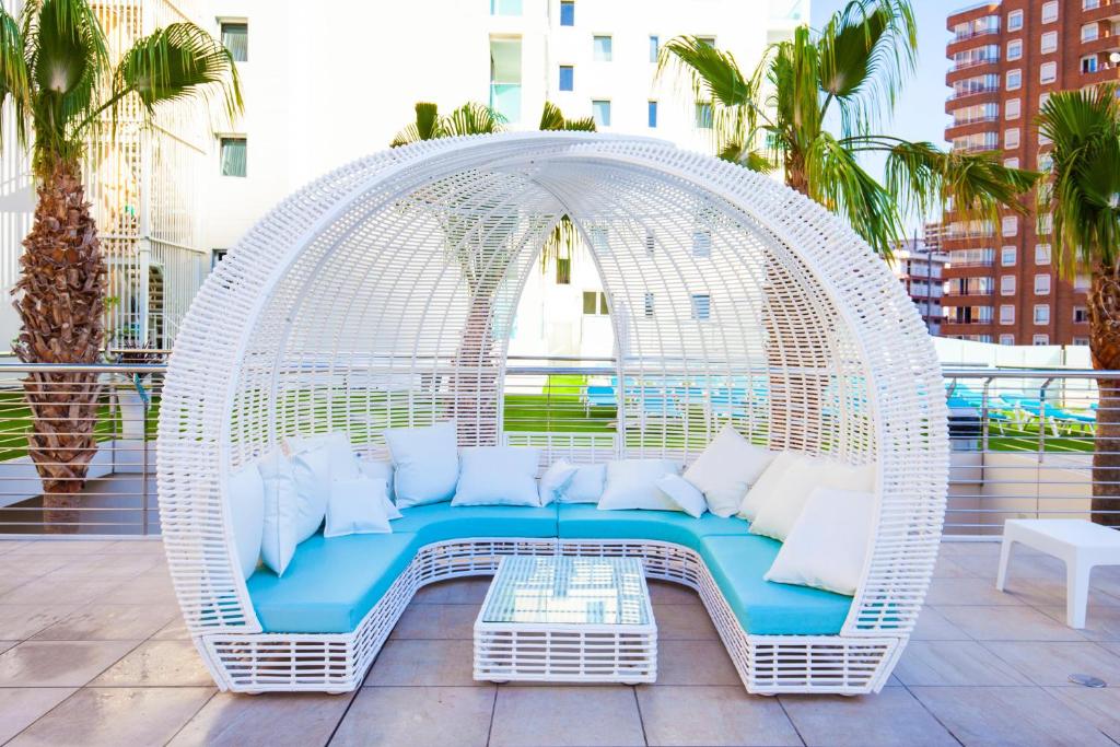 Baltais, stilīgais atpūtas komplekts ar zilo spilvenu, izvietots pie baseina, apstādīts ar palmām. Ideāla vieta relaksācijai un atpūtai.