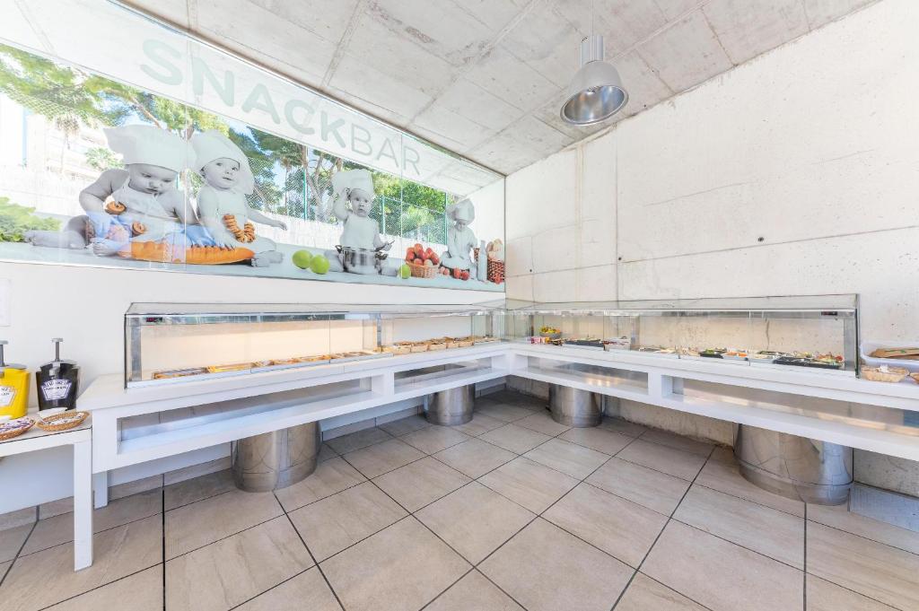 Snack bārs ar dažādām uzkodām un modernu dizainu, kas piedāvā ērtu un pievilcīgu vidi. Galdi ir pilni ar ēdieniem, kas izkārtoti skaidri un pieejami.